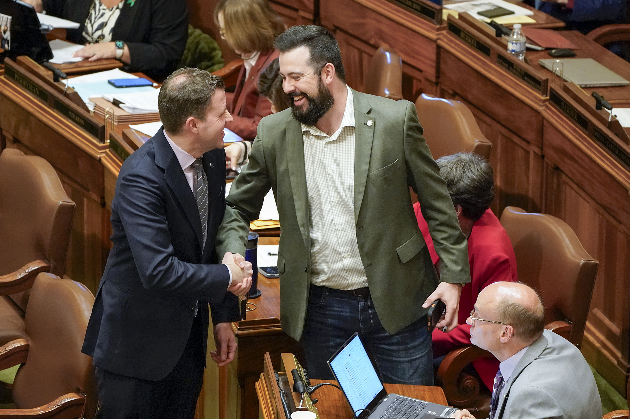 DFL Floor Leader Jamie Long, left, congratulates Rep. Spencer Igo following the passage of HF3900, which would place a proposed constitutional amendment on the ballot allowing larger annual payments to school districts and charter schools from the permanent school fund. It now goes to the Senate. (Photo by Michele Jokinen)